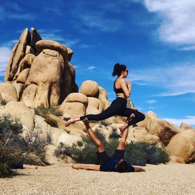 Aly flying a warrior pose on Steve in Joshua Tree National Park